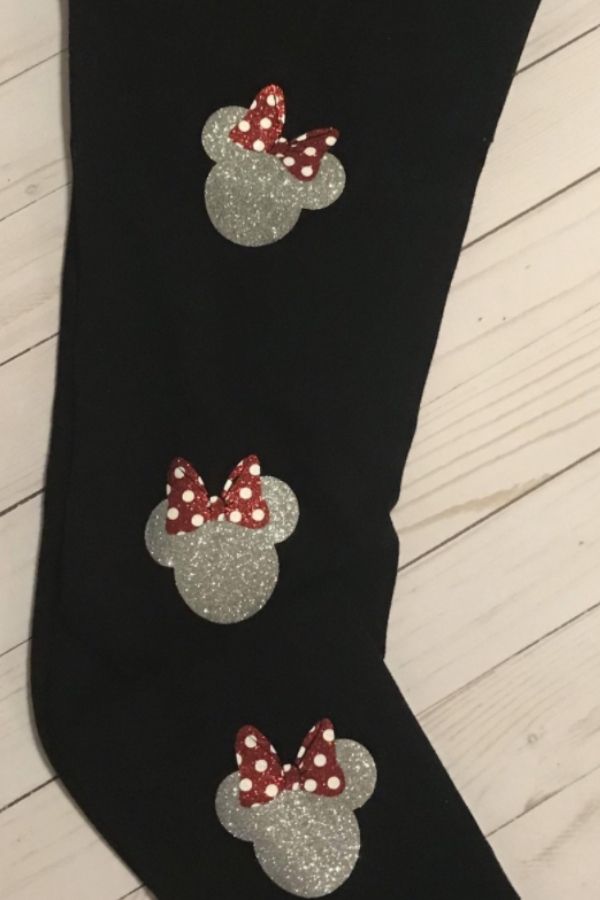 a black pair of leggings with gold sparkly Minnie heads with a red sparkly bow