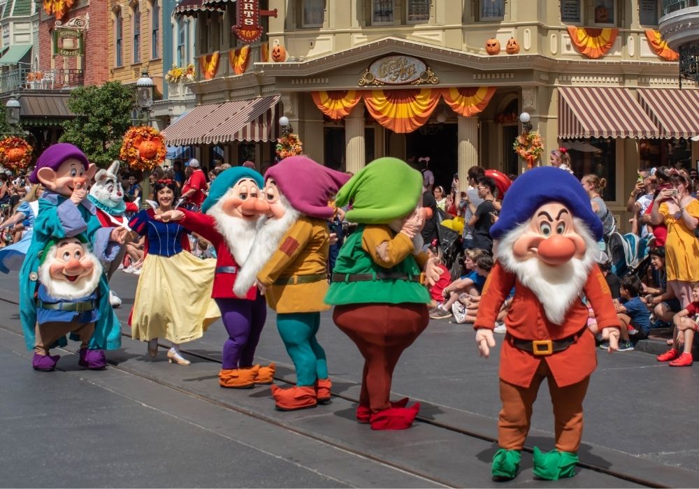 the seven dwarfs marching in a parade down Main Street at Magic Kingdom with Snow White
