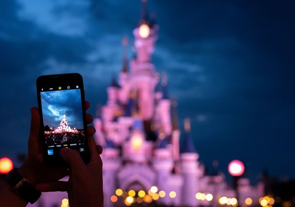 A guest takes a picture of Cinderella's Castle with their smart phone at Disney World, rather than using the Memory Maker service