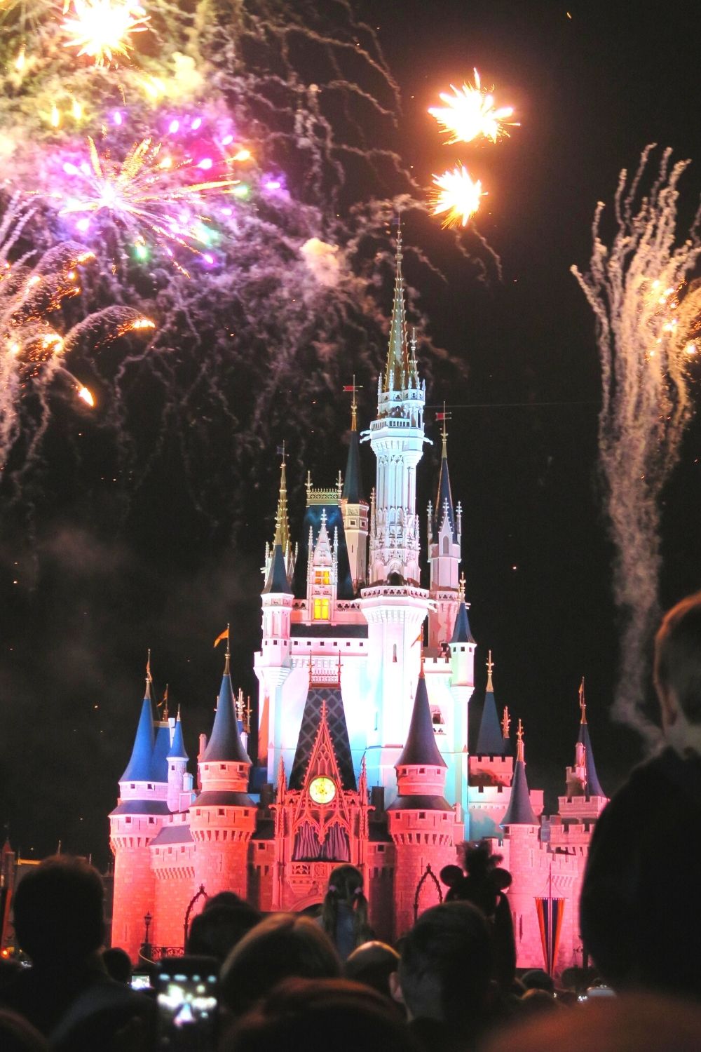 Cinderella Castle at Disney World lit up at night with fireworks overhead