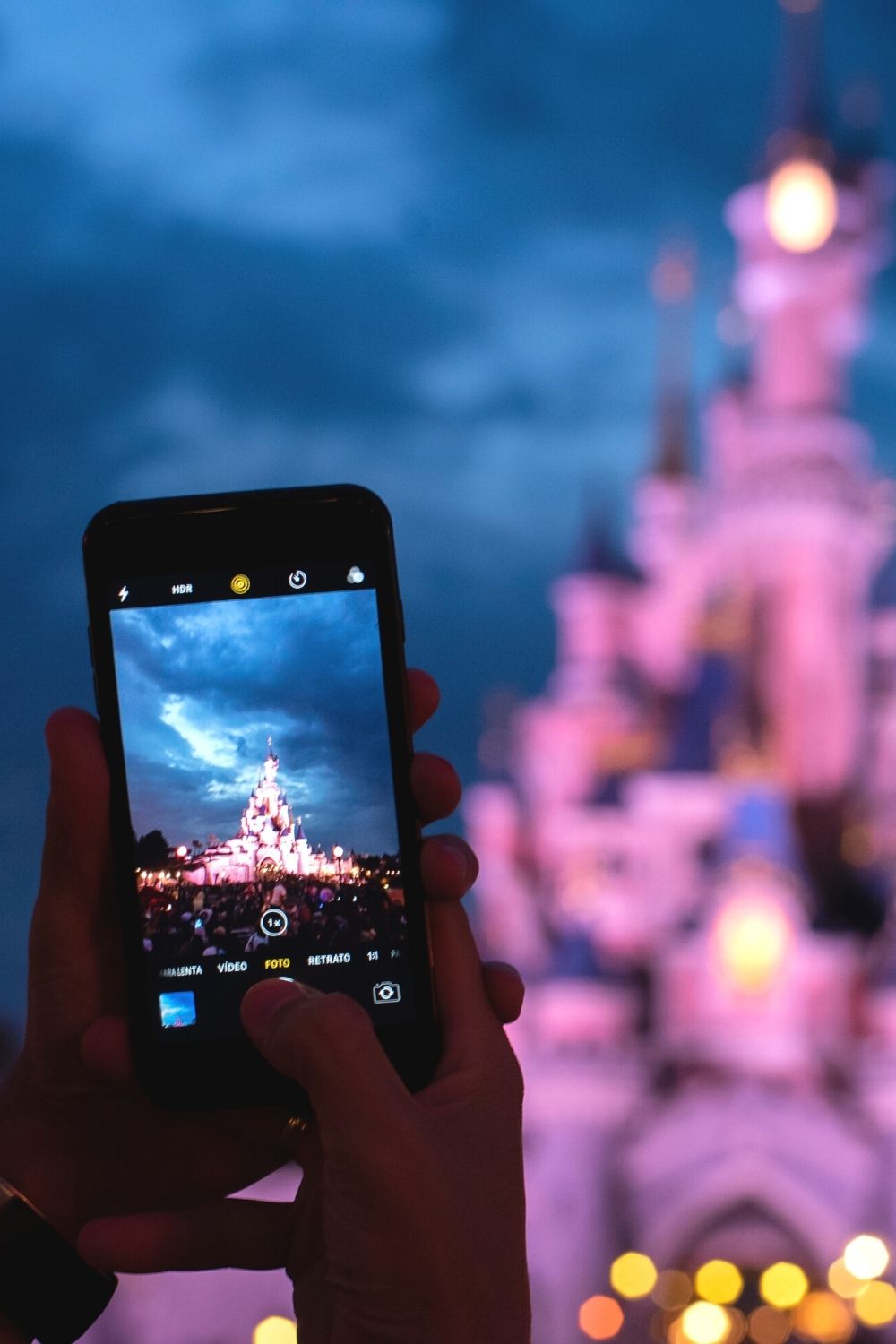 a Disney guest uses their phone camera to take a photo of Cinderella's Castle