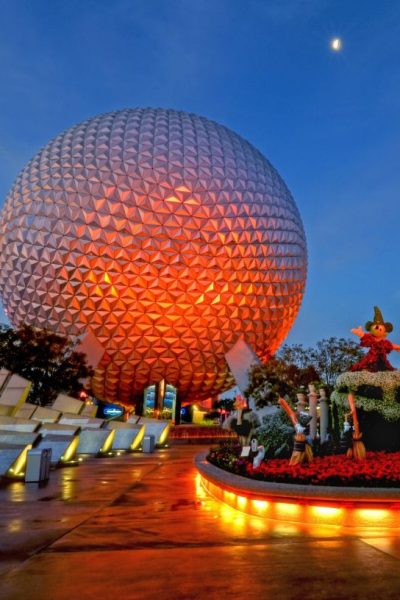Spaceship Earth at Epcot in Disney World is lit up at night, with a red-orange light shining on it