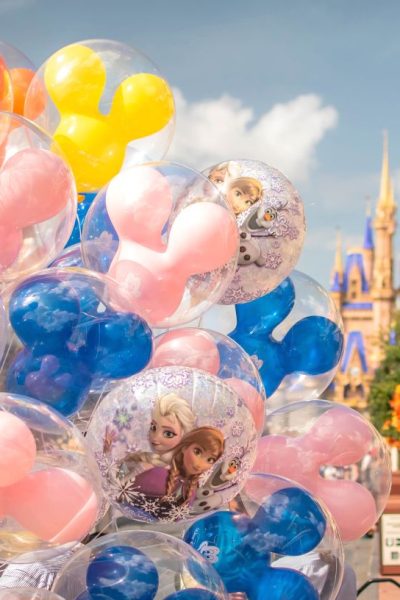 close-up view of Disney World balloons for sale on Main Street USA, including pink, yellow, blue, and orange Mickey Mouse balloons, plus Frozen-themed character balloons.