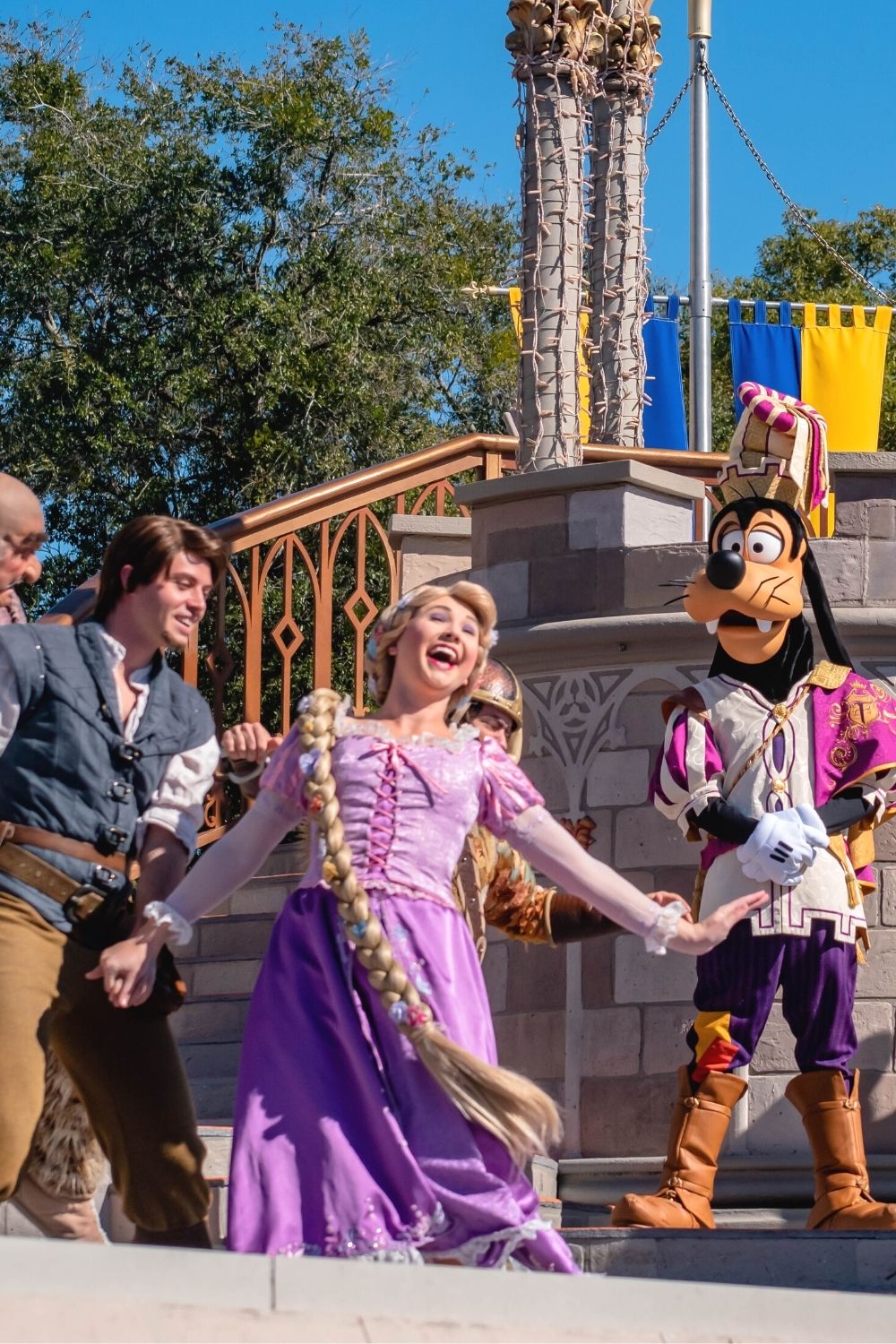 Rapnzel sings next to Flynn Rider and Goofy during a stage show at Magic Kingdom in Disney World